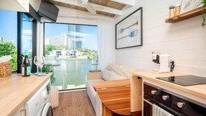 A compact kitchen with a view of a river, a dining area, and a small seating space. - Tiny Home in the heart of Broadbeach-River Views! (Broadbeach Waters)