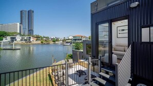 A modern balcony with a view of a river and cityscape, including tall buildings and a marina. - Tiny Home in the heart of Broadbeach-River Views! (Broadbeach Waters)
