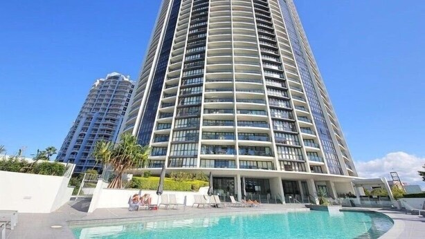 A high-rise hotel with a pool area, multiple balconies, and a clear blue sky. - City & Hinterland Views – 1BR Retreat in Sierra Broadbeach (Gold Coast)