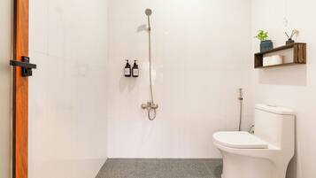 Een moderne badkamer met een douche, toilet en twee flessen toiletartikelen aan de muur.