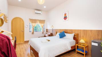 Une chambre d’hôtel avec un lit en bois, une petite table avec une lampe, une armoire et une fenêtre avec des rideaux.