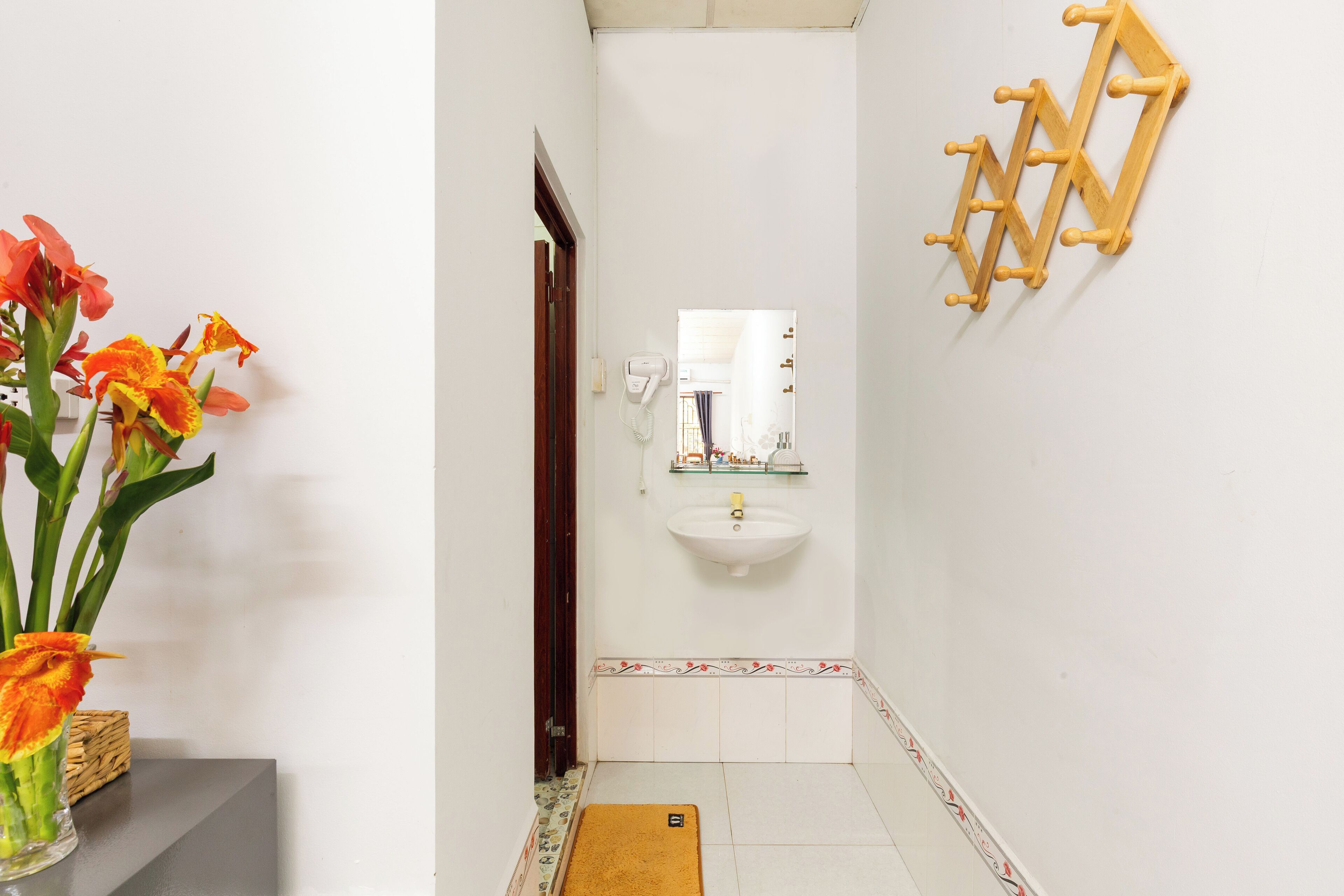 Un baño con un lavamanos blanco, un espejo y un estante de madera.