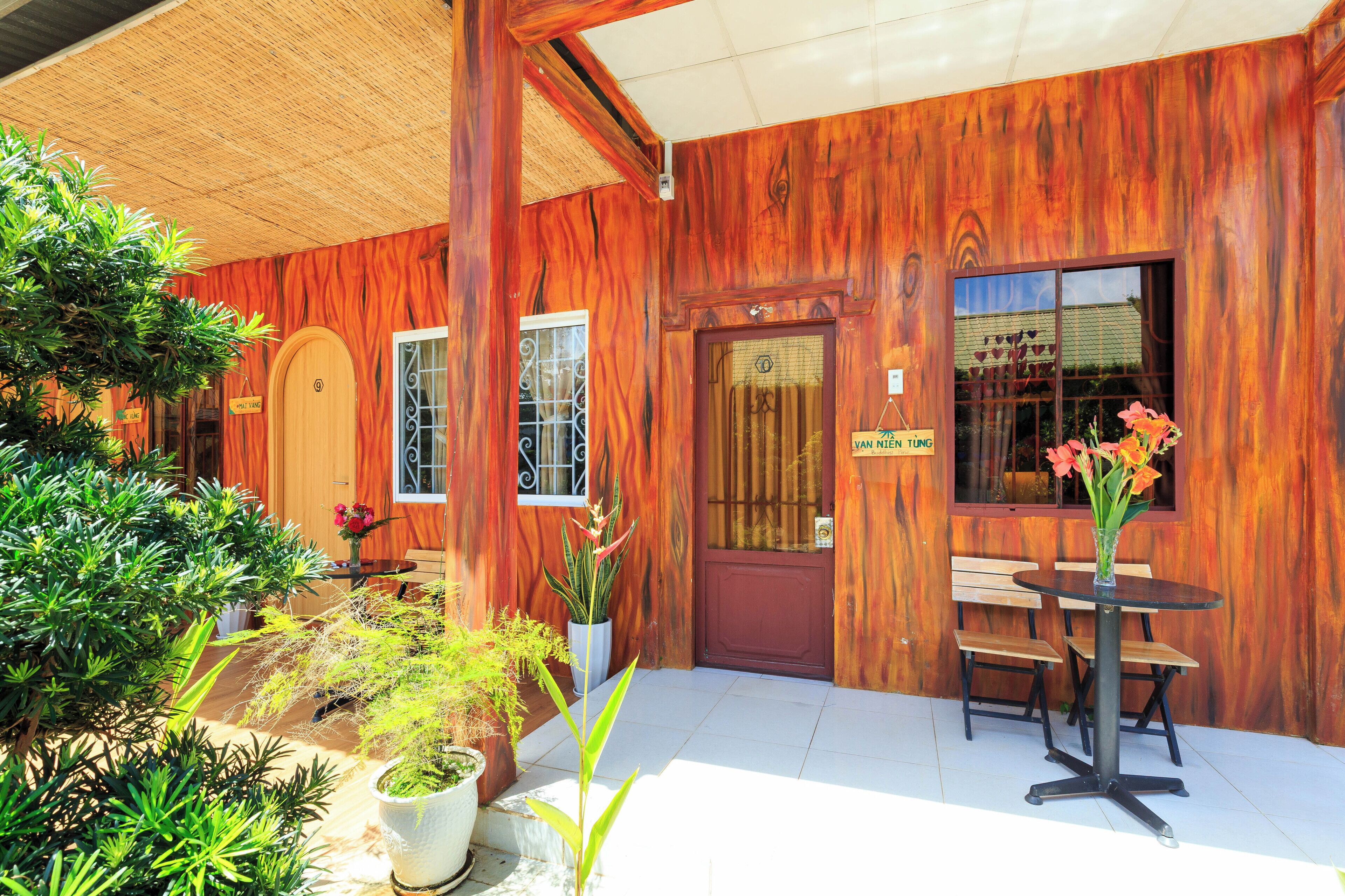 Fachada de madera con puerta, ventanas y una pequeña mesa con sillas.