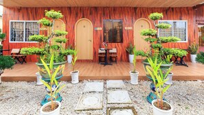 A wooden building with a covered porch, potted plants, and a seating area. - SaDec Farmstay (Sa Dec)