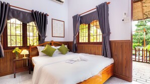 A neatly made bed with a wooden headboard, a bedside table with a lamp, and a window with curtains. - SaDec Farmstay (Sa Dec)