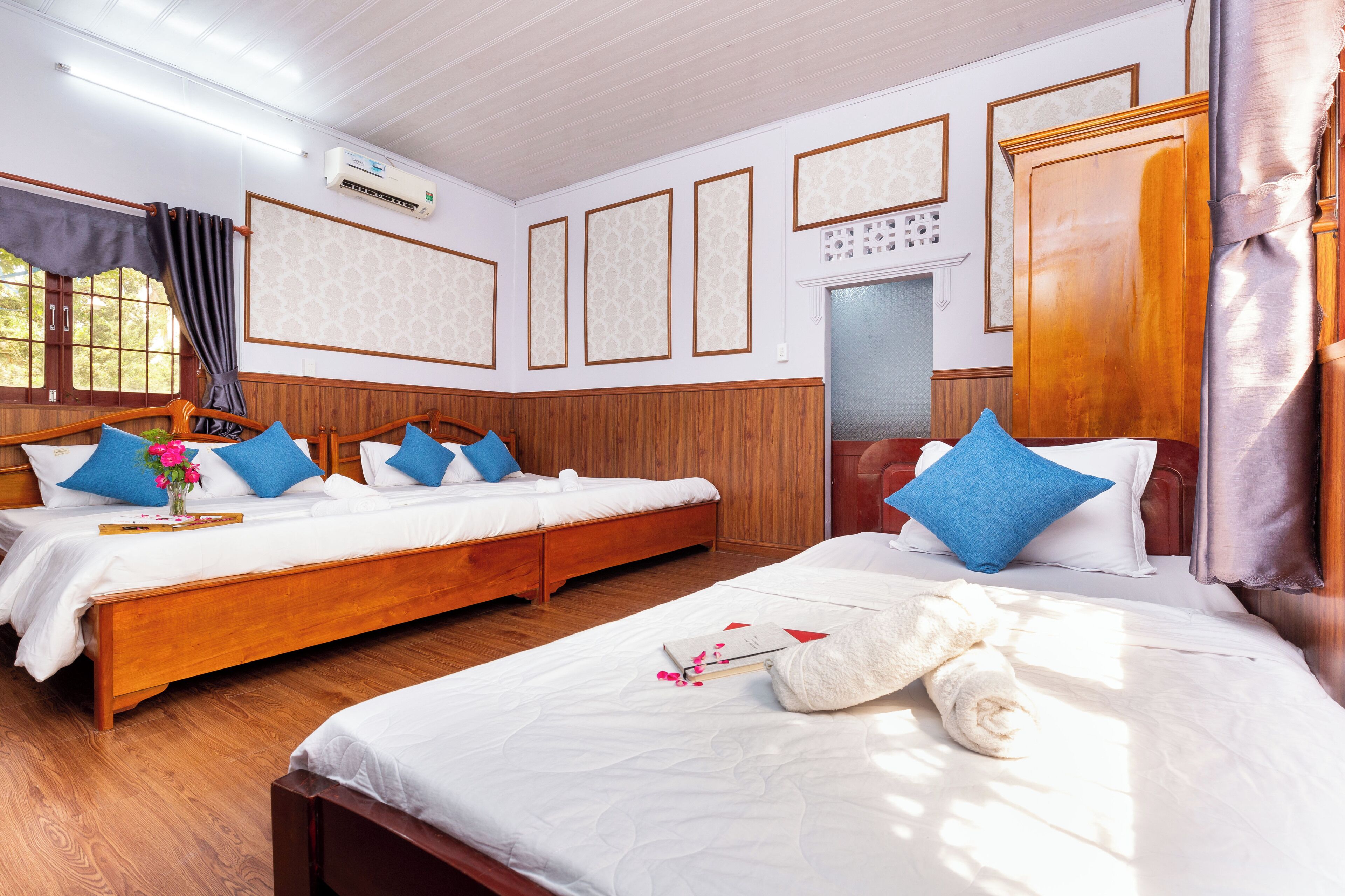 A hotel room with two beds, wooden paneling, and a large wardrobe.