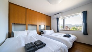 Camera d'albergo con due letti, testiere in legno, biancheria bianca e vista sull'esterno.