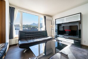 Un salon moderne avec un canapé, un téléviseur et une vue sur la ville.