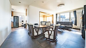 Una camera d'albergo moderna con zona pranzo, divano e vista sulla città.