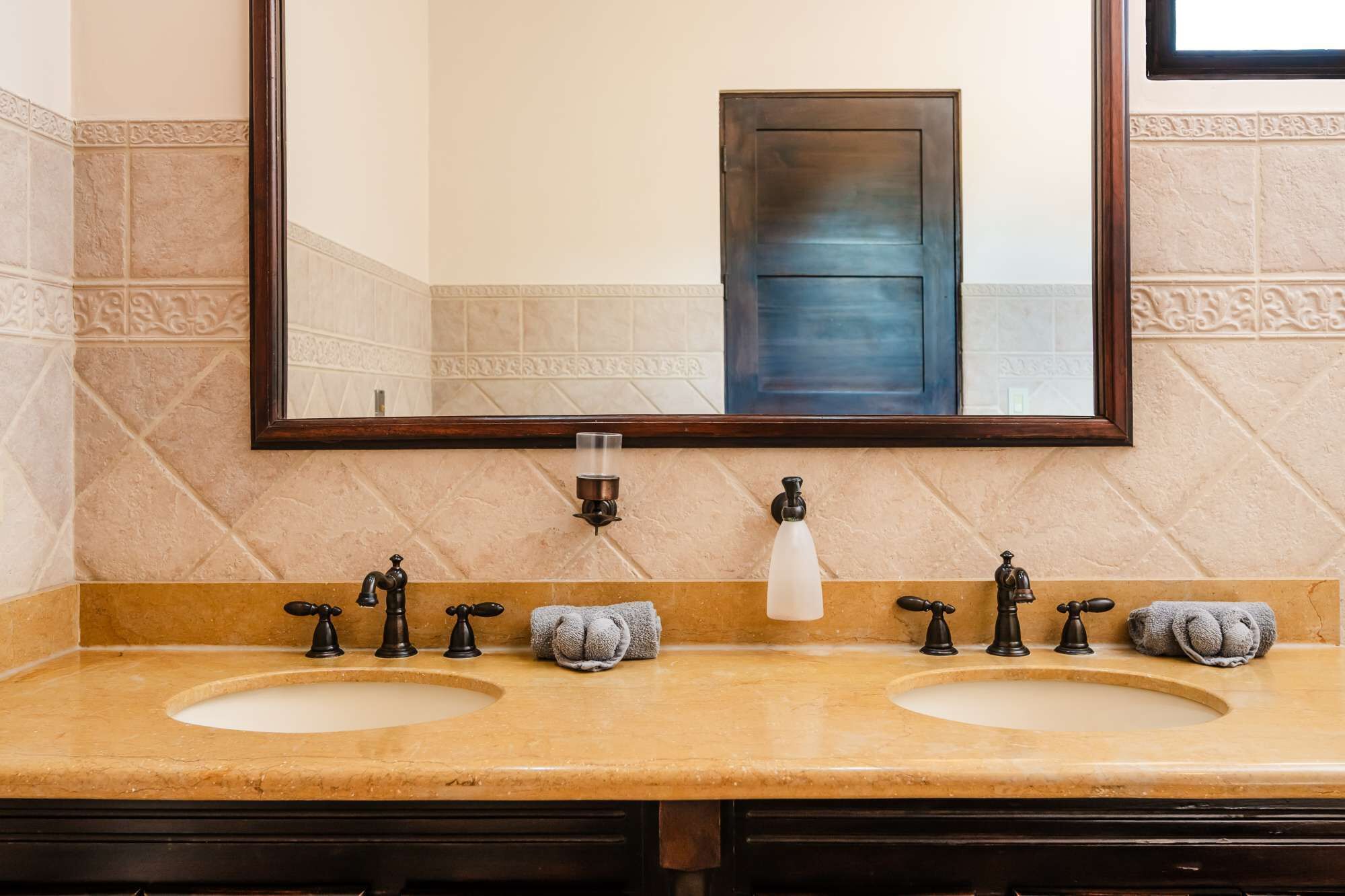 Un baño con dos lavamanos, un espejo y un perchero para toallas.