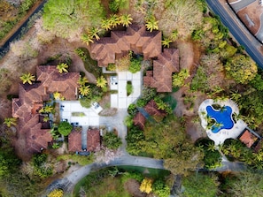 Vista aérea de una zona residencial con varias casas, una piscina y abundante vegetación.
