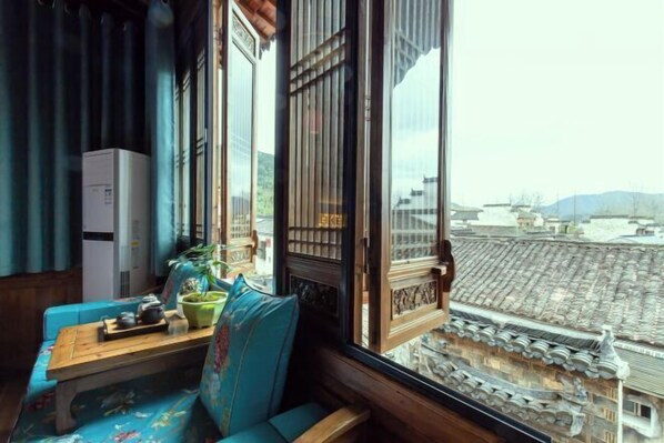 A room with a traditional wooden bench, a small table with tea set, and a view of traditional rooftops. - Hongcun Yixian County emblem Hostel (Yi County)