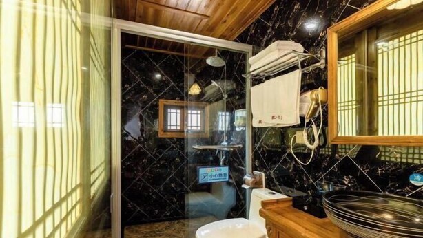 Ein Badezimmer mit Duschkabine aus Glas, Toilette, Waschbecken und Spiegel.