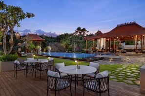 Zona junto a la piscina con mobiliario exterior y vista al agua.