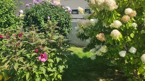 A residential garden with various flowering plants and a house in the background. - Hotel and guesthouse good value for money (Hochkirch)