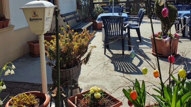 An outdoor patio area with potted plants, outdoor seating, and a sign indicating a restaurant. - Hotel and guesthouse good value for money (Hochkirch)