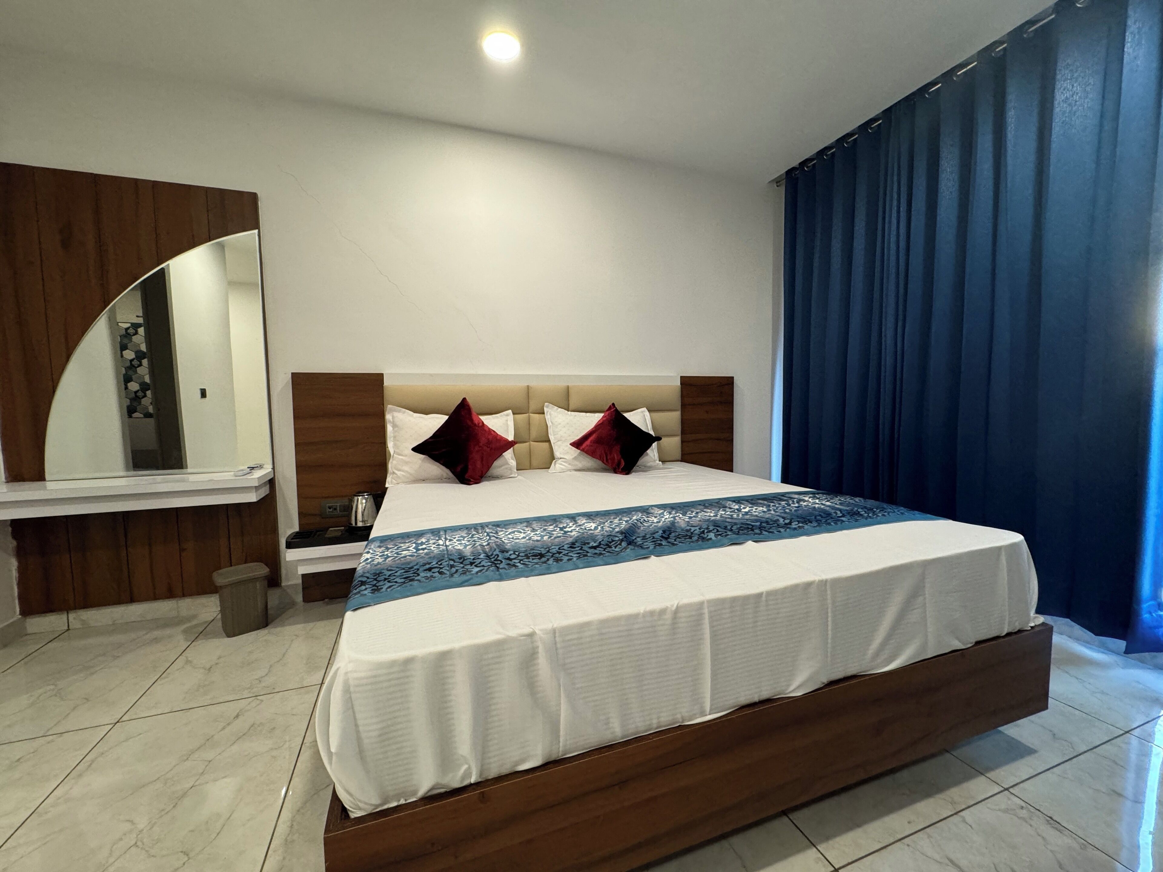 A modern hotel room with a large bed, wooden headboard, and a nightstand.