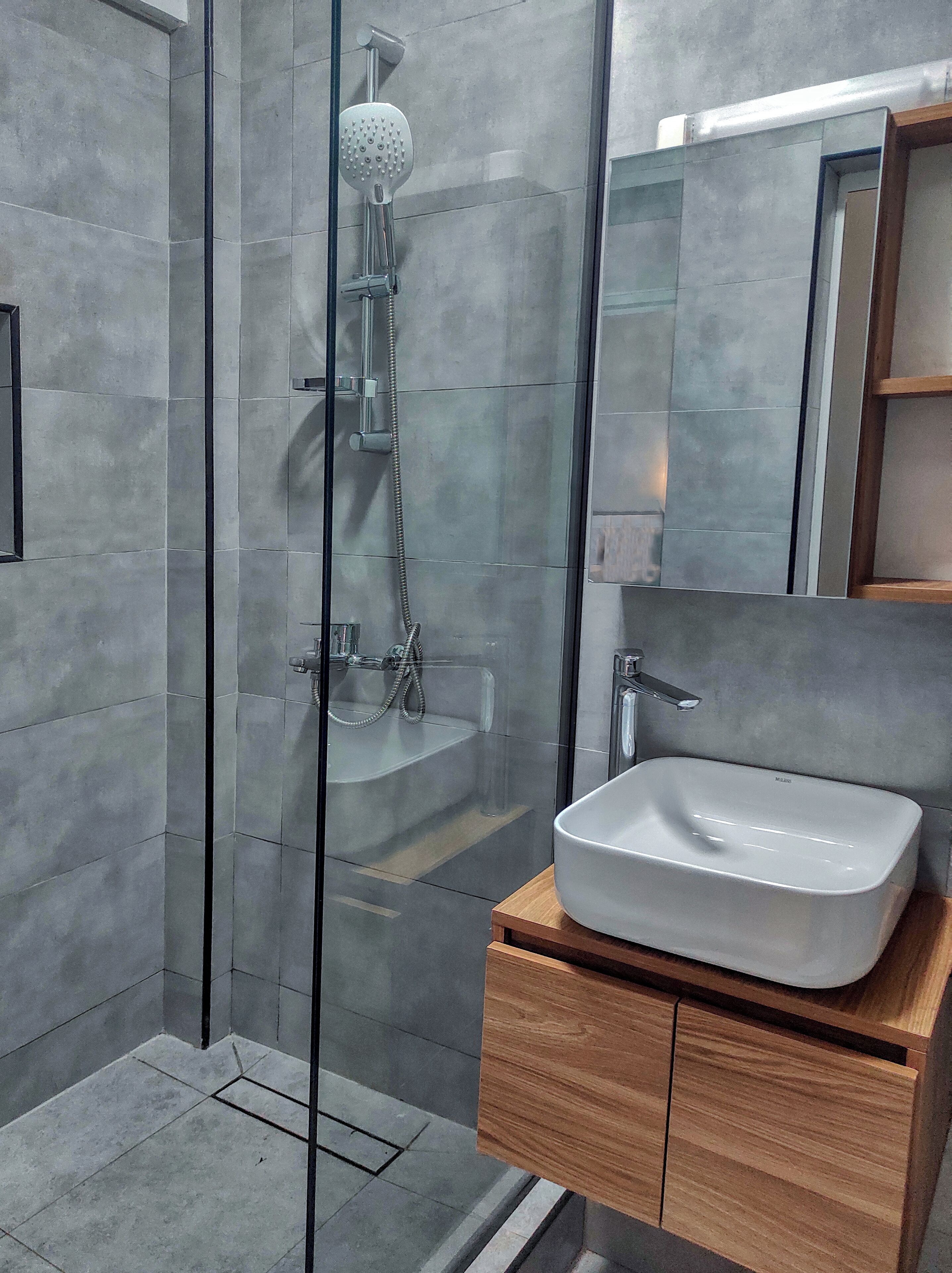 Une salle de bain moderne avec une douche à parois de verre, un lavabo blanc et un meuble-lavabo en bois.