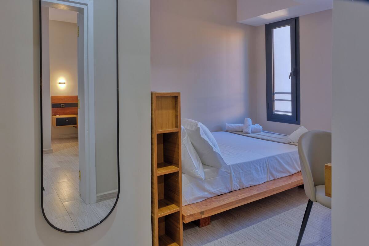Un dormitorio moderno con una cama de madera, una mesita de noche y un espejo grande.