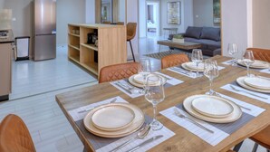 A dining area with a wooden table set for four, surrounded by orange chairs. - ZEN Hôtel (Nosy Be)