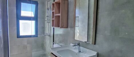 Uma casa de banho moderna com chuveiro, sanita e lavatório.