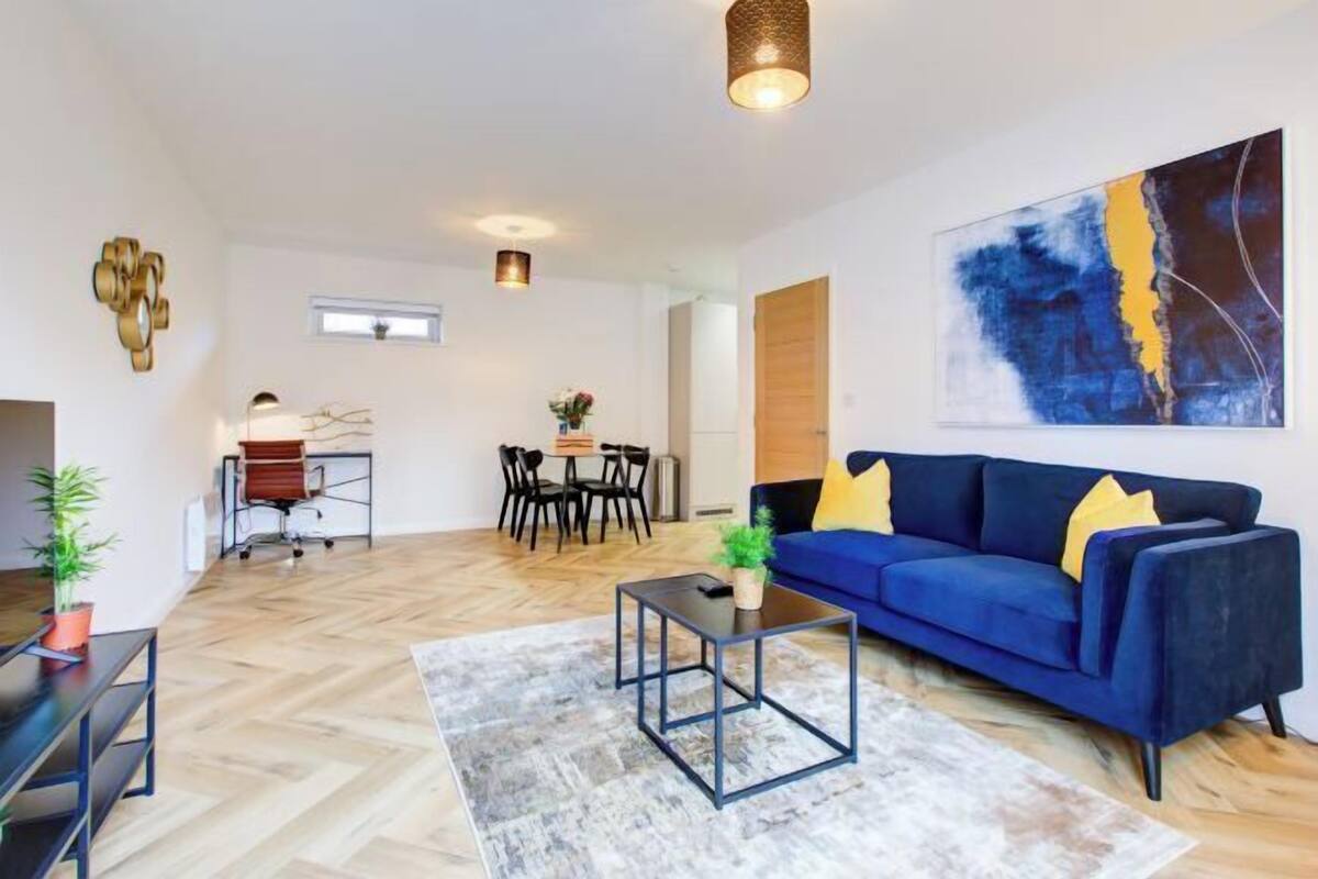 Un salon moderne avec un canapé bleu, une table basse et un coin repas comprenant des chaises et une table.