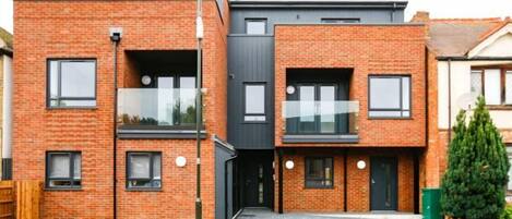 Un immeuble résidentiel moderne à deux étages, doté d’une façade en briques, de grandes fenêtres et d’un toit plat.