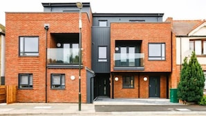 Un bâtiment moderne à deux étages, construit en briques, avec un toit plat, de grandes fenêtres et un balcon bien visible.