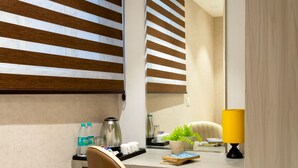 A modern bathroom with a vanity, a mirror, a yellow lamp, and a chair. - Hotel Stay Vista (New Delhi)