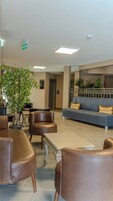 Un hall con asientos, una recepción y un letrero de salida verde.