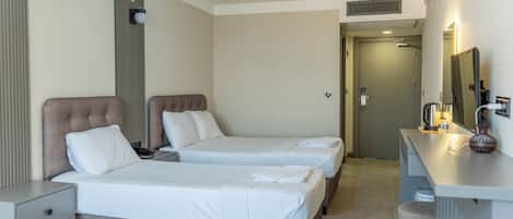 A hotel room with two beds, a desk with a mirror, and a door leading to a bathroom.