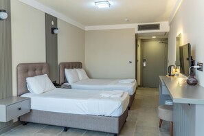 A hotel room with two beds, a desk with a mirror, and a door leading to a bathroom. - Grand Cennet Beach Hotel (Edremit)