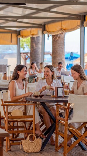 A group of people seated at an outdoor table with a view of the sea. - Grand Cennet Beach Hotel (Edremit)