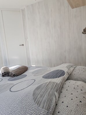 A bedroom with a bed, pillows, and a door. - Attractive, fully equipped mobile home for 4 people   (Samoëns)