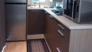 Cocina pequeña equipada con refrigerador, estufa, microondas y lavaplatos.
