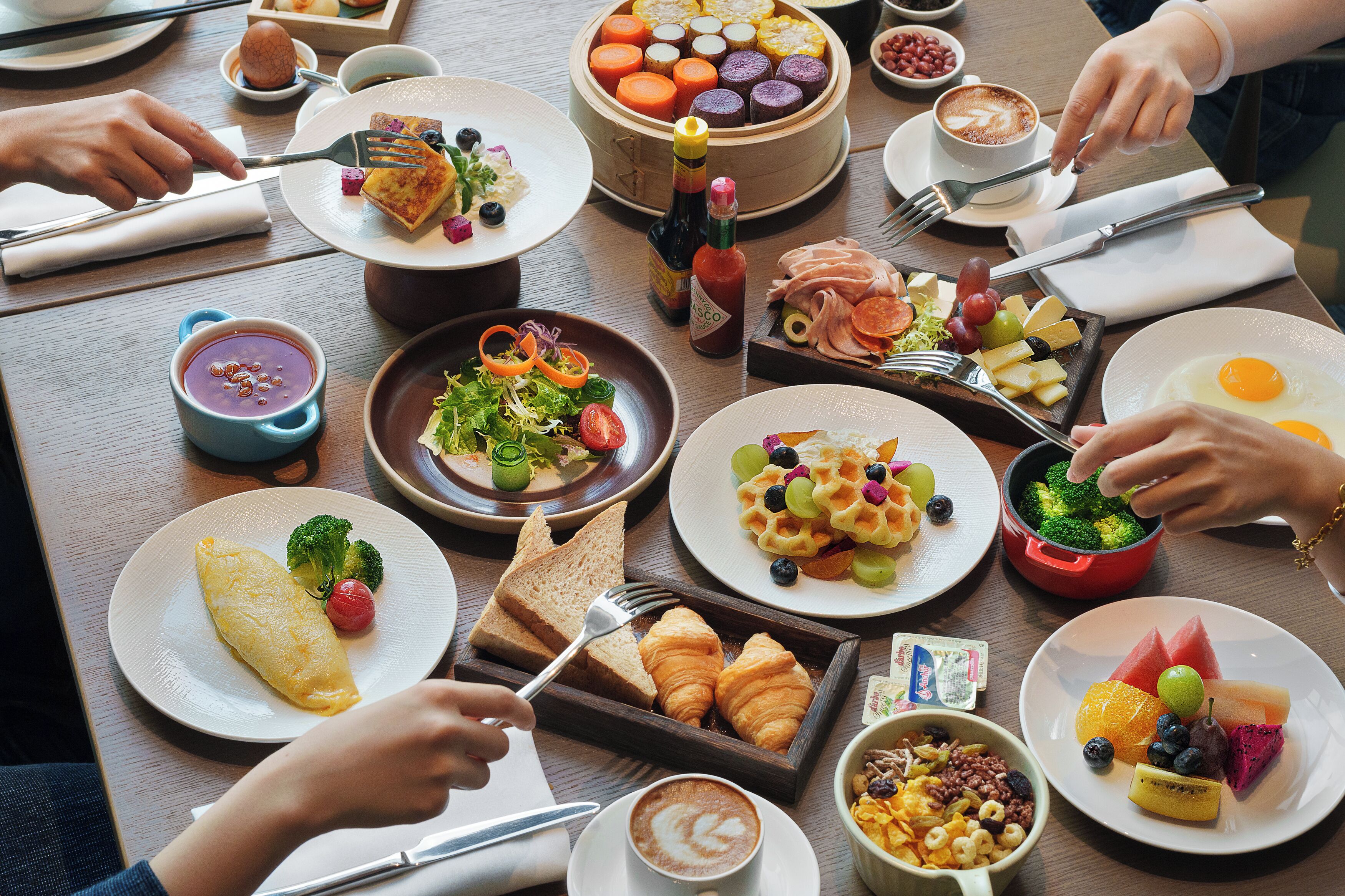 Una mesa con diversos platos de desayuno, como huevos, tostadas y fruta.
