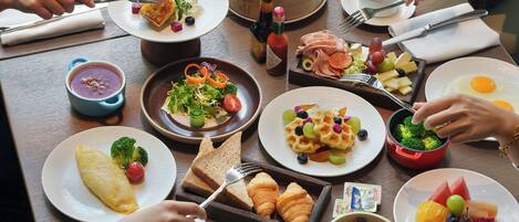 Una mesa con diversos platos de desayuno, como huevos, tostadas y fruta.