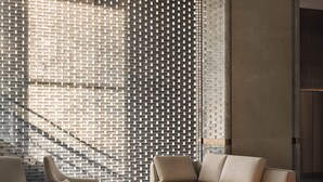 Una sala de estar moderna con una pared estampada, un sofá, una mesa de centro y una lámpara.