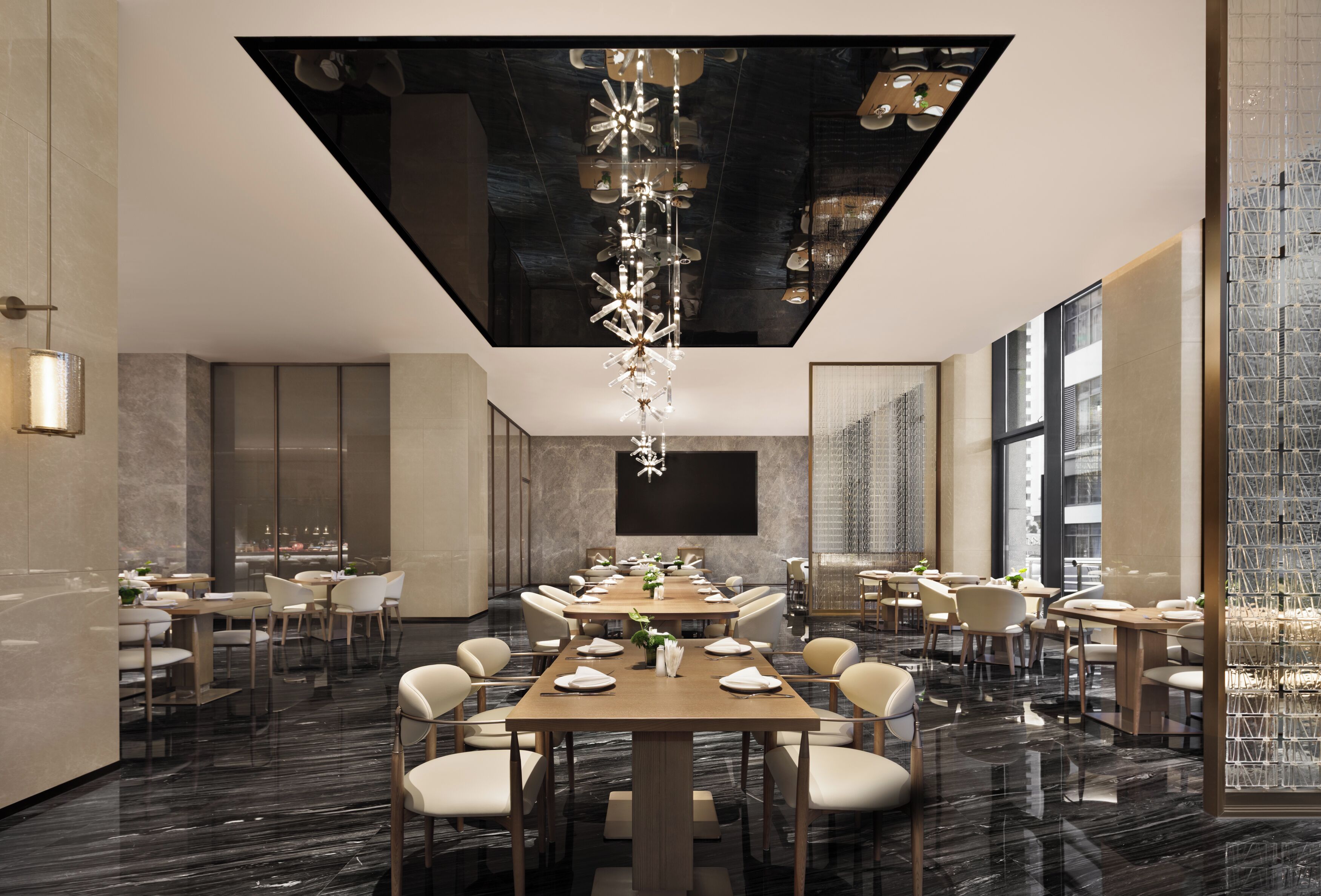 A modern dining area with a long table set for a meal, surrounded by chairs, and a unique chandelier.