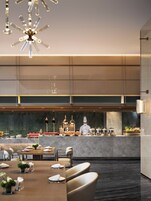 Un restaurante moderno con un chef en la barra, paredes de mármol y una larga mesa de comedor con sillas.