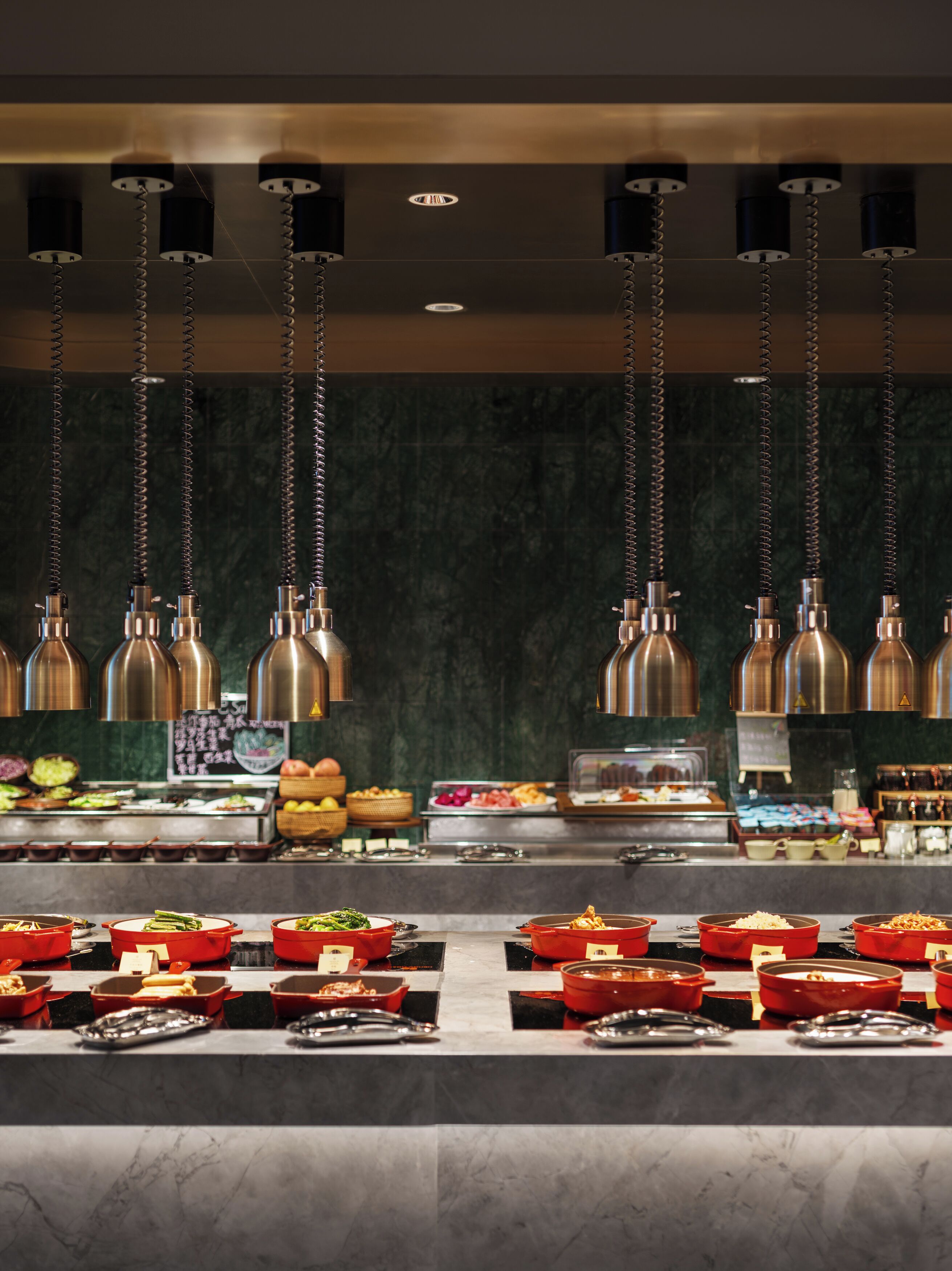 Un buffet avec plusieurs présentoirs de nourriture et des lampes suspendues décoratives.