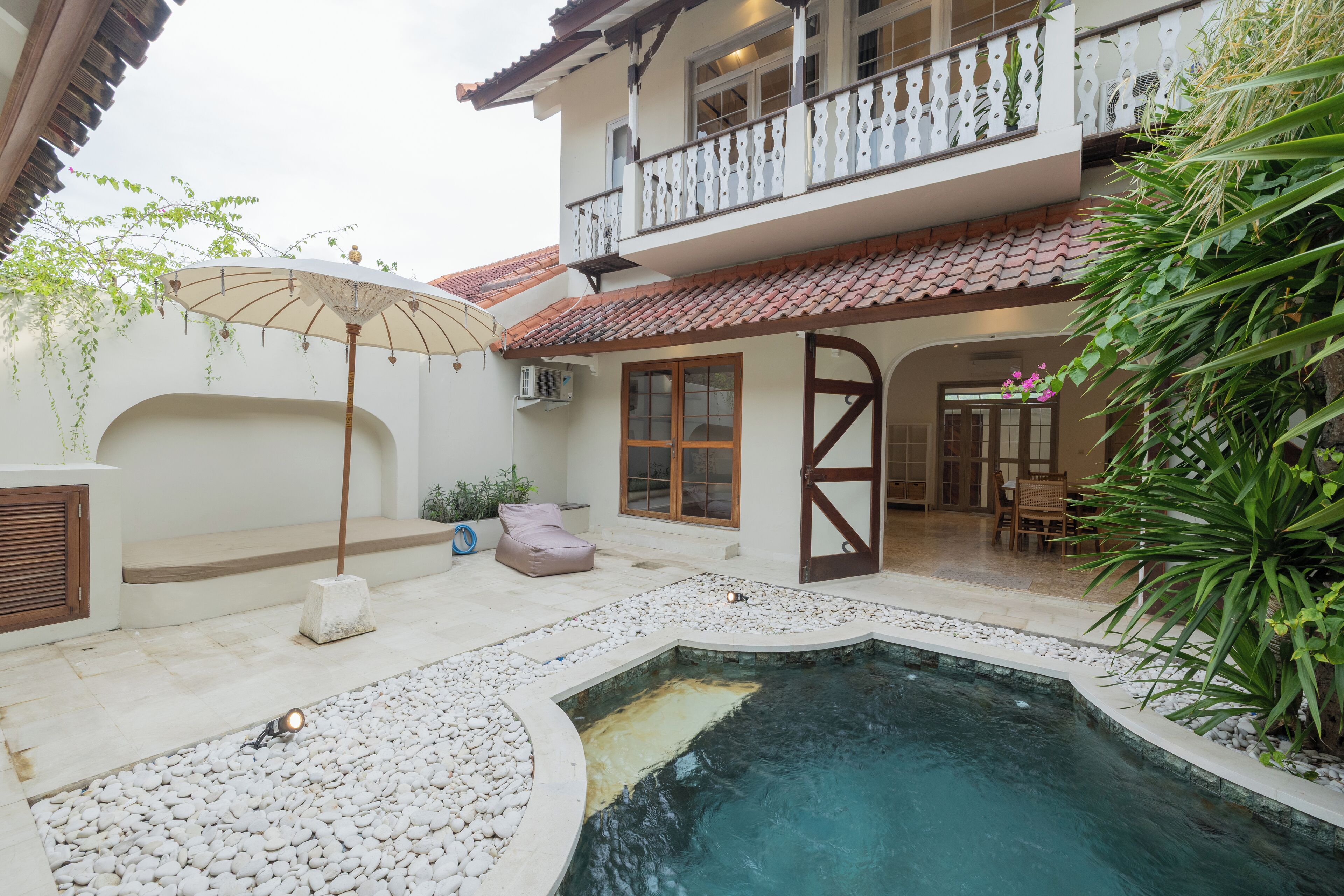 Une cour avec une piscine, un espace salon couvert et un balcon.