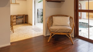 A room with a wooden floor, a wicker chair, a desk, and a large window. - Charming Two Bedroom Villa Near Seminyak (Seminyak)