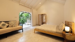 A bedroom with a bed, a sofa, a nightstand, and a wooden wardrobe. - Charming Two Bedroom Villa Near Seminyak (Seminyak)