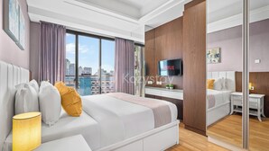 Ett modernt hotellrum med en stor säng, ett skrivbord, en TV och utsikt över staden.