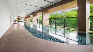 En modern inomhuspool med ett trädäck och stora fönster som ger utsikt över grönområden.