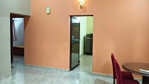 Et rum med et marmorbelagt gulv, en rød stol, et bord, en dør og et vægur.