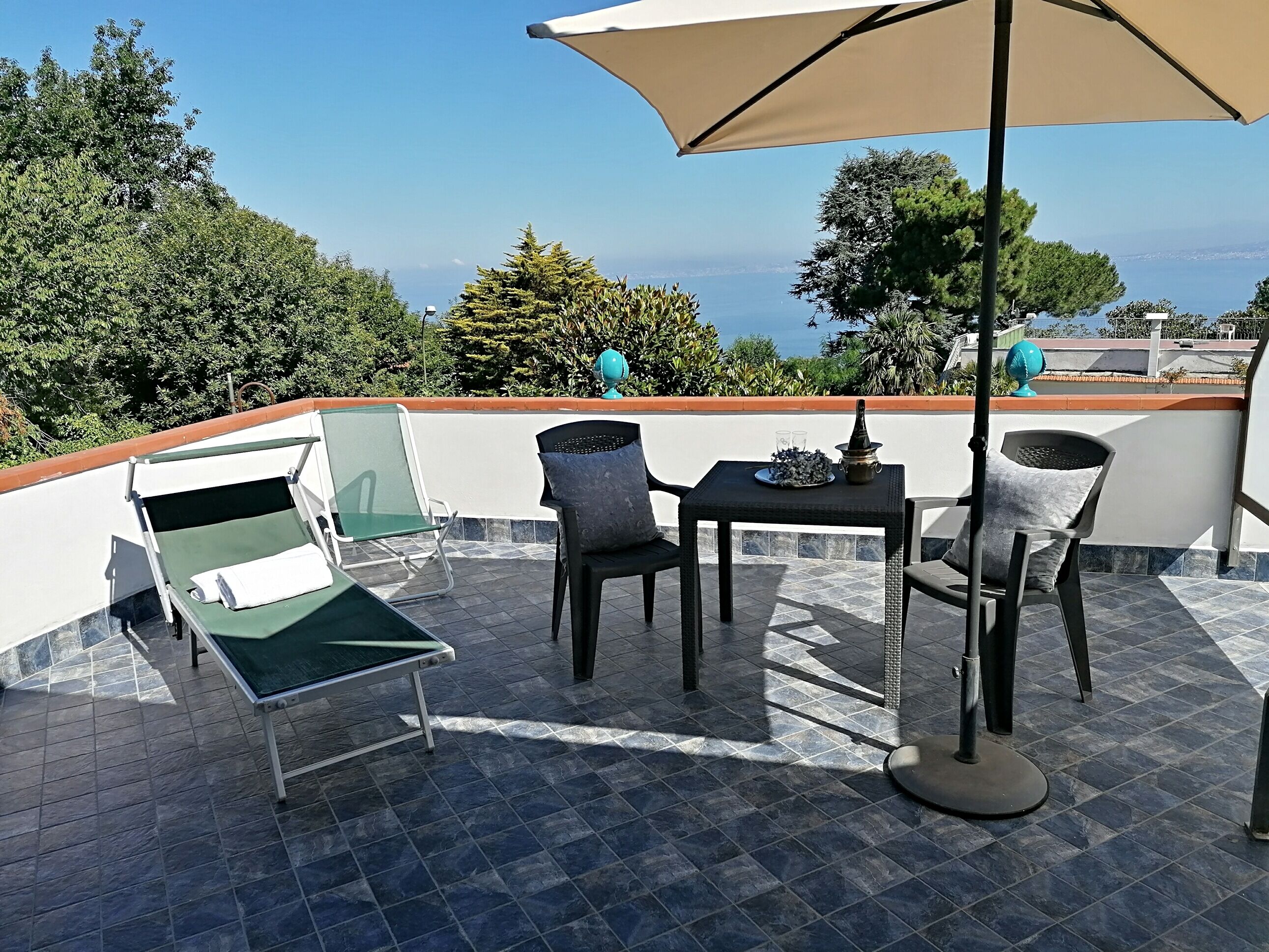 A terrace with a table, chairs, and a lounge chair.