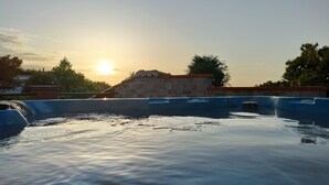 Ein Schwimmbecken mit einer Steinmauer und einem Gebäude im Hintergrund.