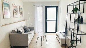 A modern living room with a grey sofa, a white coffee table, and a black metal shelving unit. - Le Wilson - Modern, comfortable duplex (Vannes)